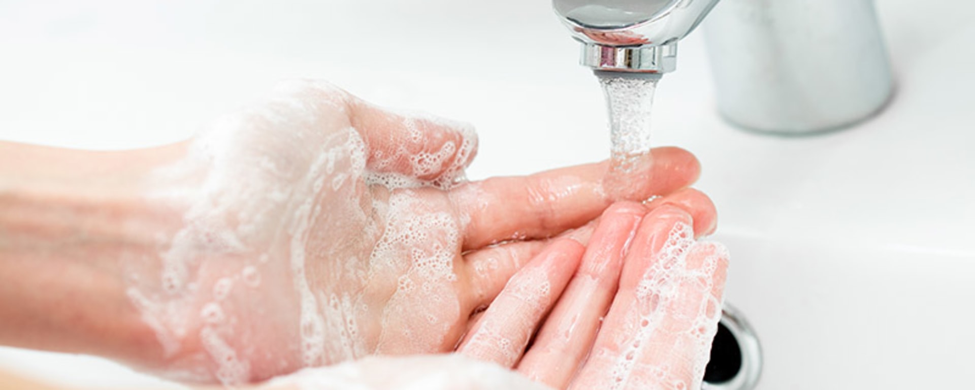 Eine Person wäscht sich die Hände mit einer Seife, die Corona visrus symbolisiert.