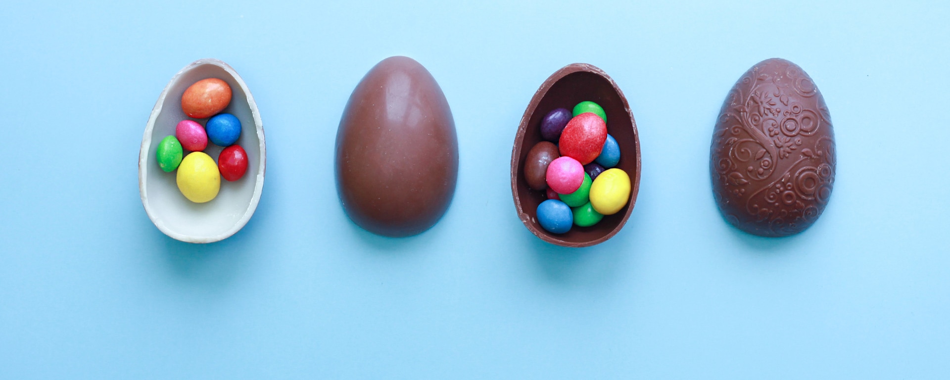 Four halves of Easter eggs lie on a light blue surface.