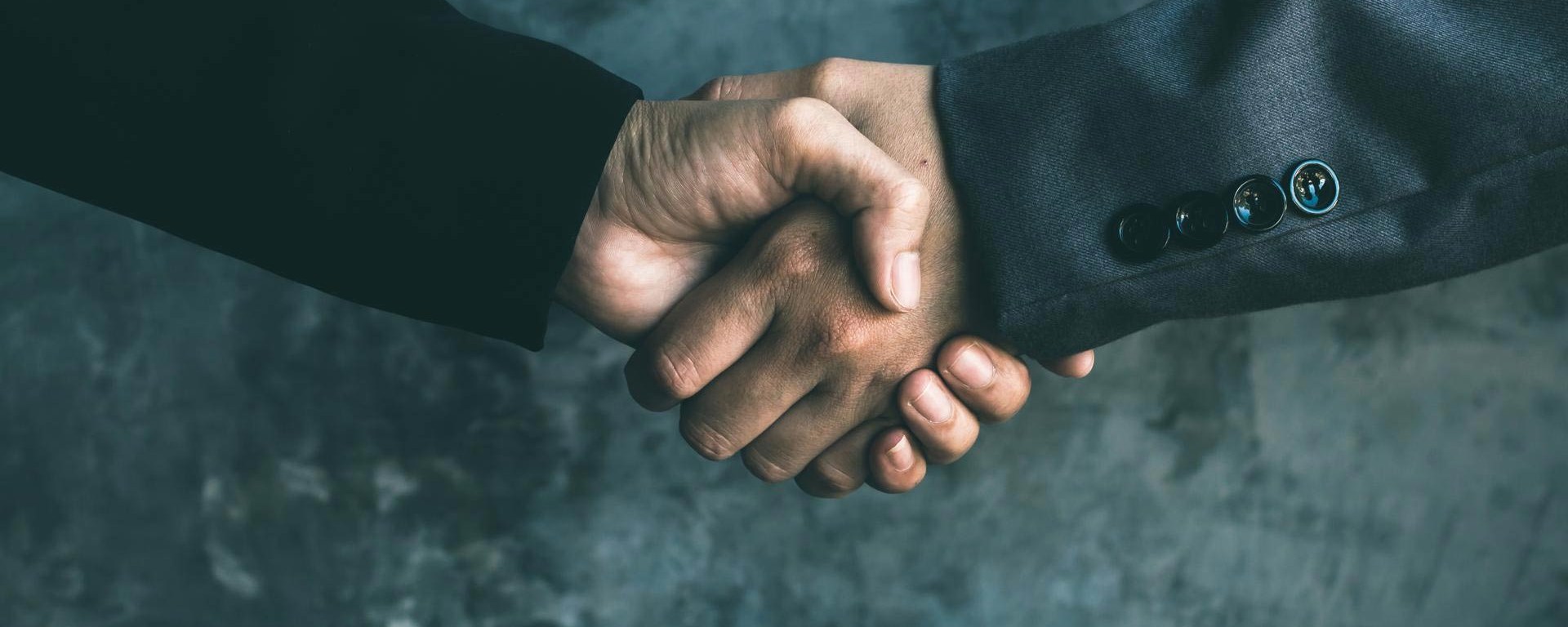 Two businessmen in suit shake hands in business relationship