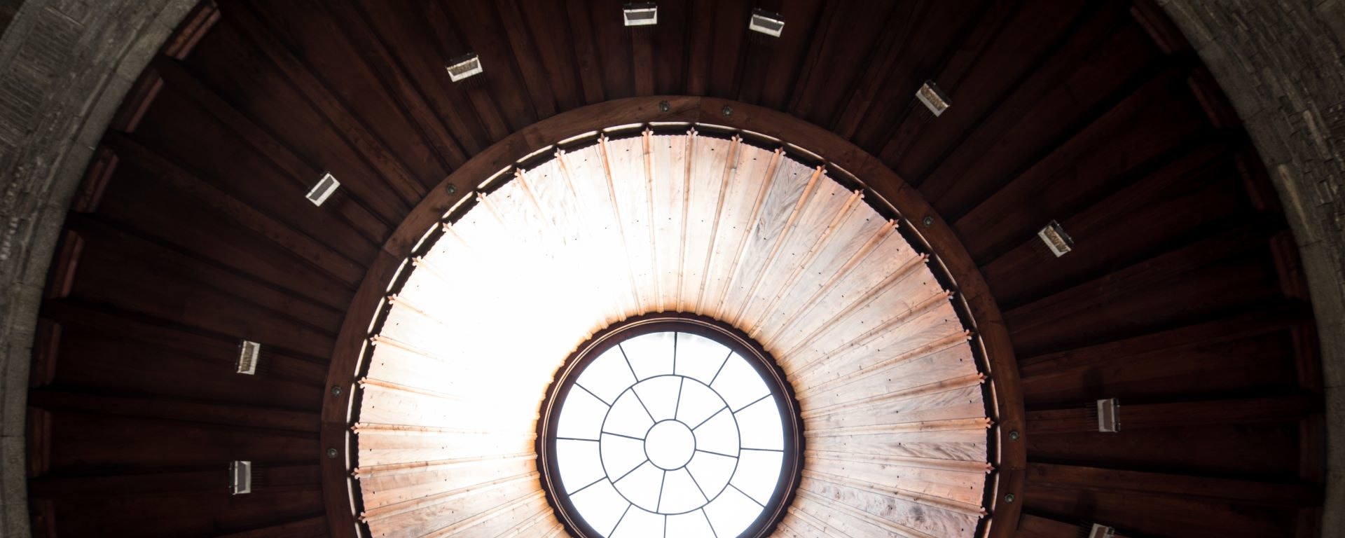 Gros plan architectural d'une lucarne circulaire au milieu d'un plafond en dôme en bois avec un design géométrique