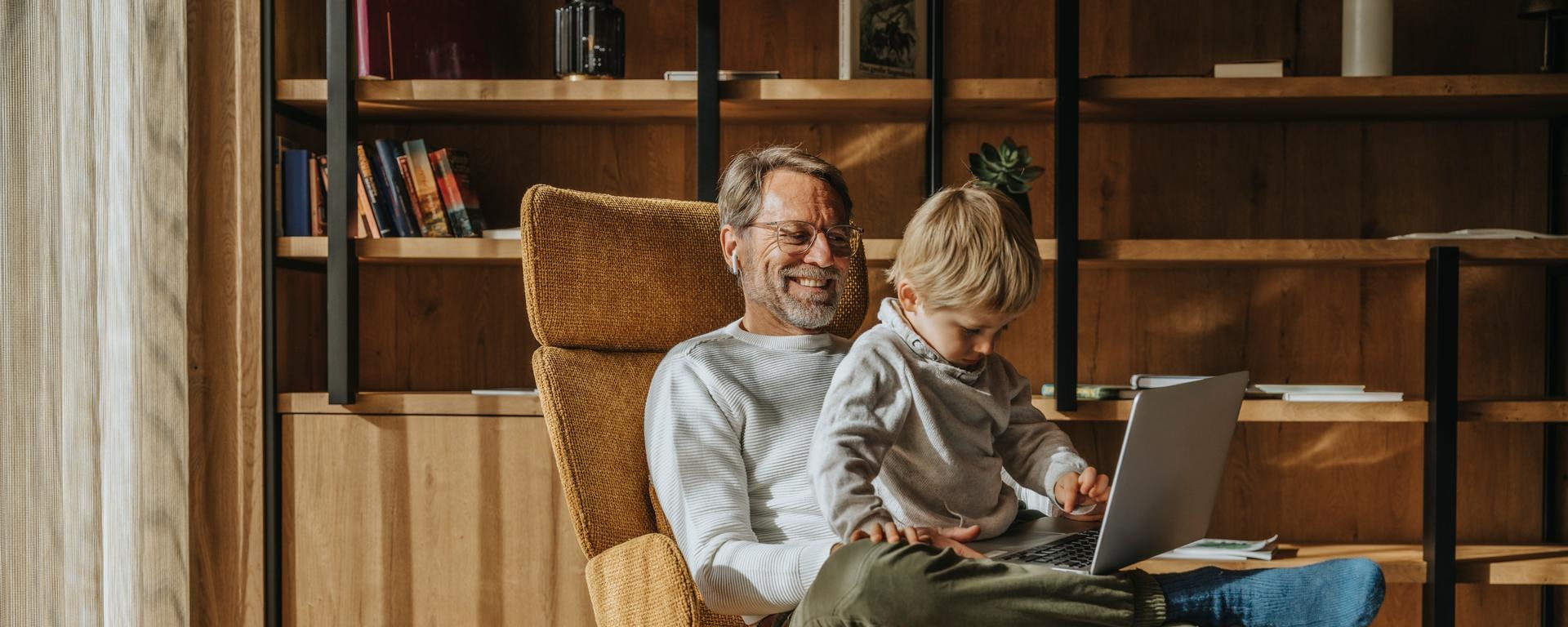Life insurance at Vontobel - father with his son and computer on his lap in a cozy living room