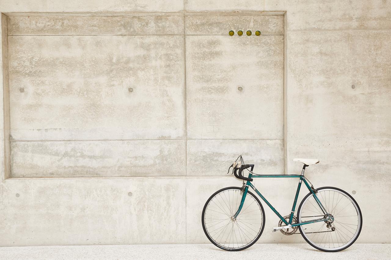 A green racing bike leaning against a concrete wall