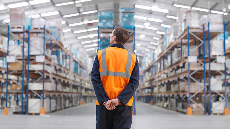 Man with orange vest standing in the warehouse