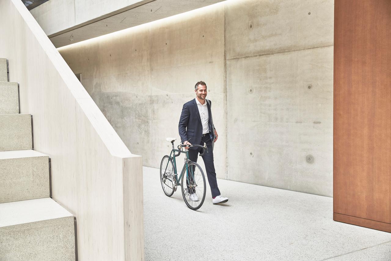 A young man guides his bicycle through office space