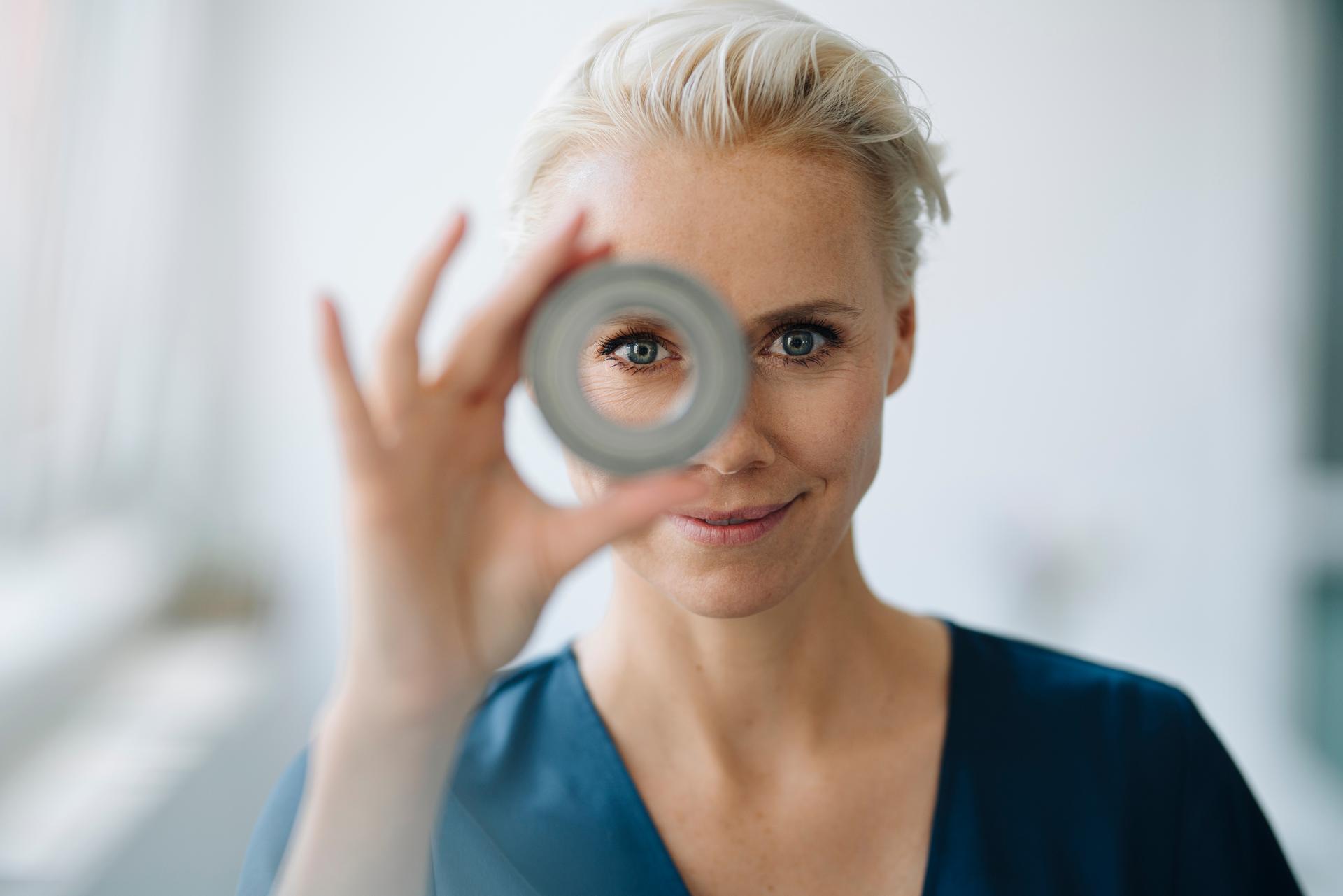 A woman holding a circular object in front of her face.