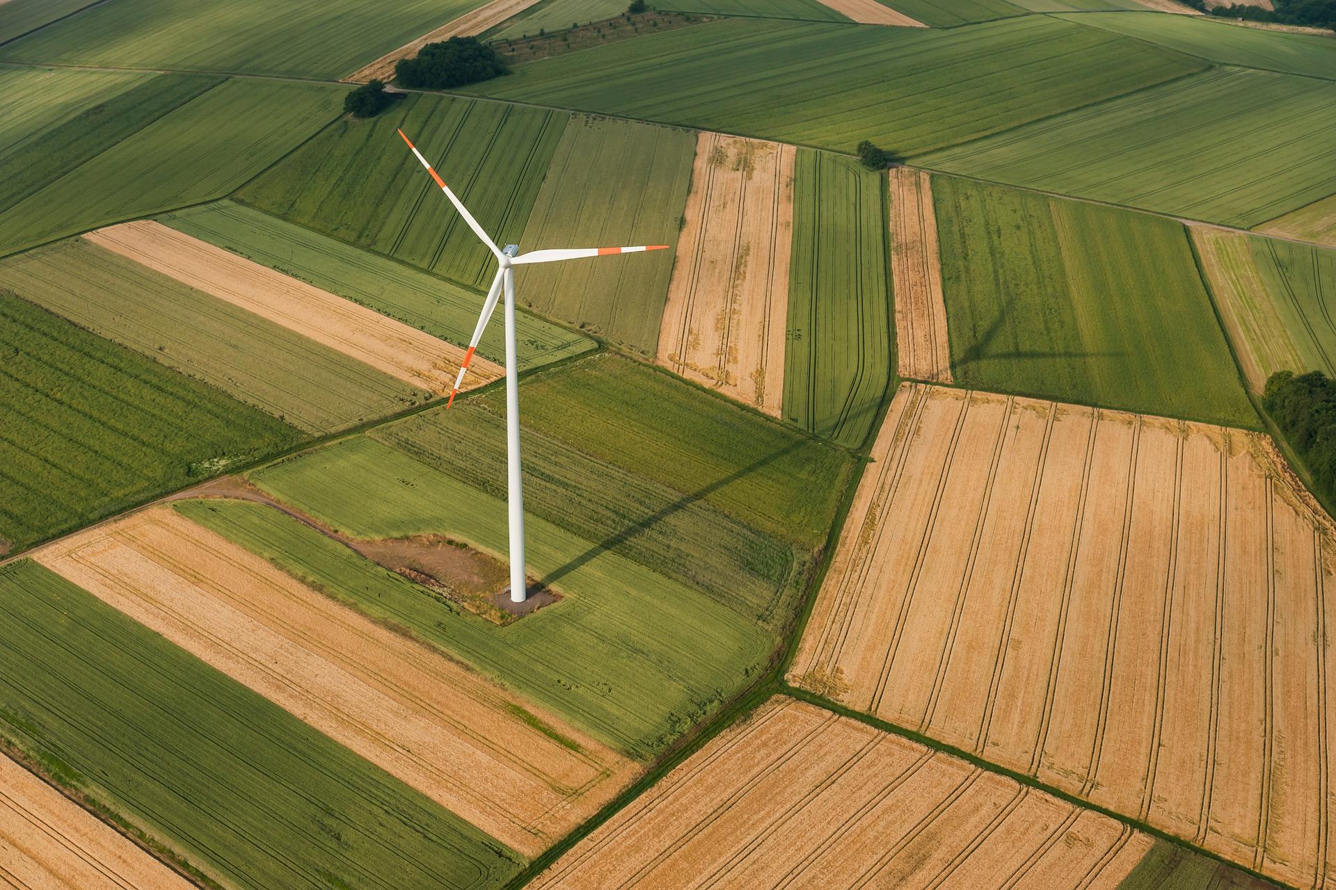 View from above of a wind turbine in the center of a field, generating clean energy and symbolizing ESG.