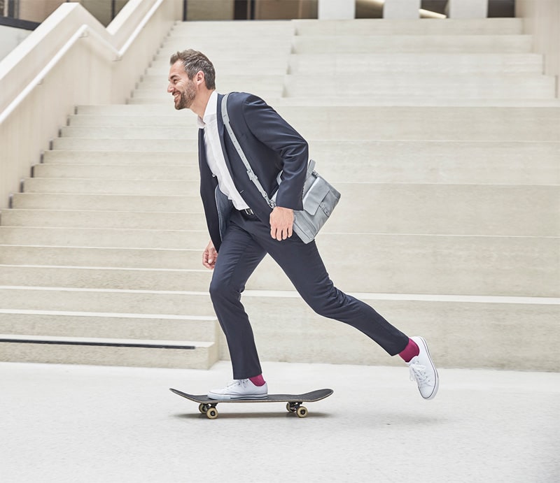 A young businessman is riding a skateboard.