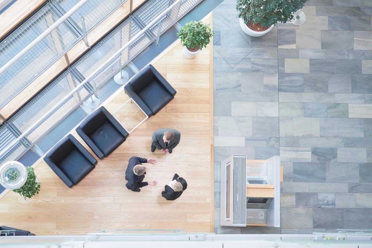 Bird's eye view of 3 business people discussing in the entrance area, symbolizing Vontobel's Lombard credit solutions.