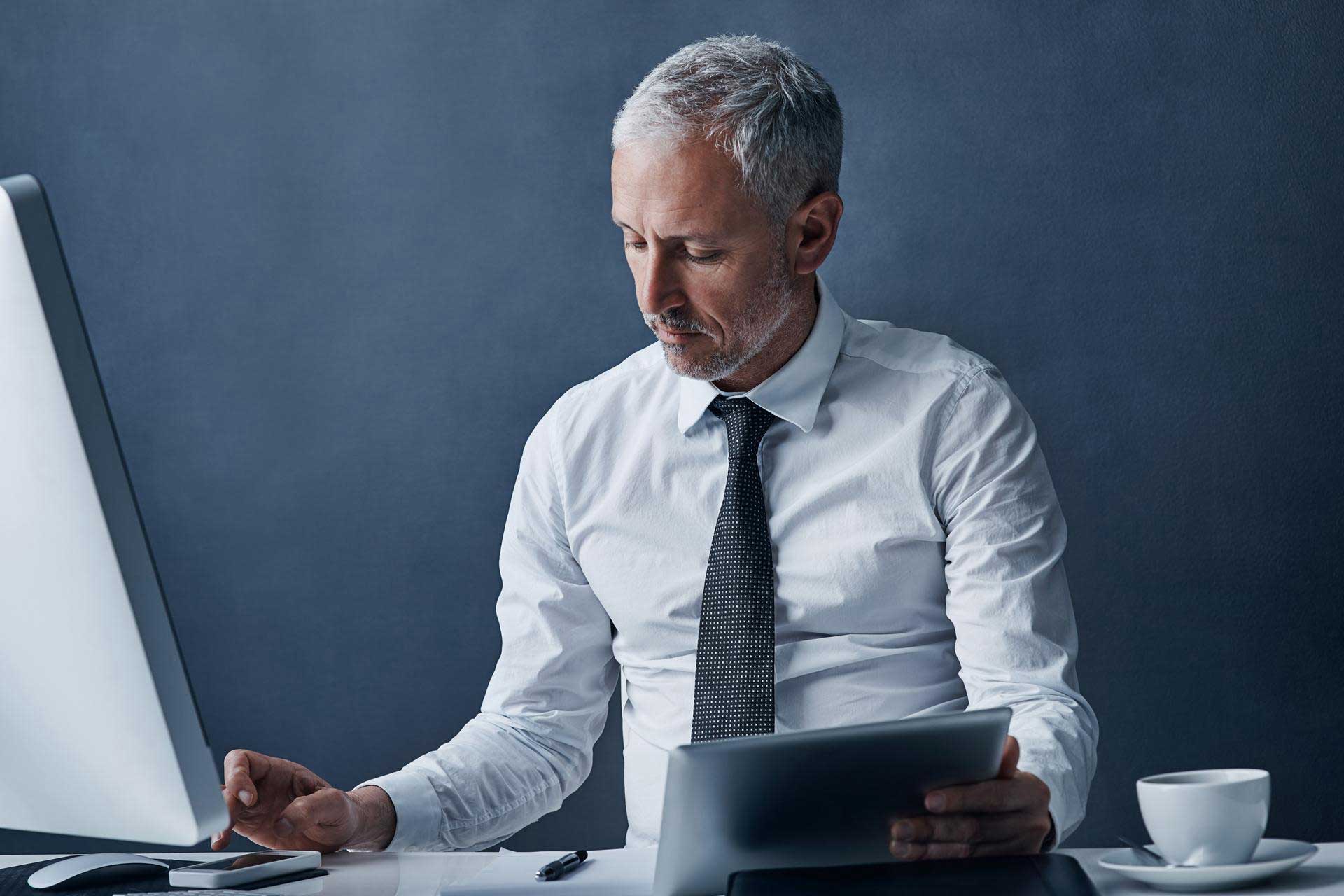 A businessman in a white shirt sits at a computer
