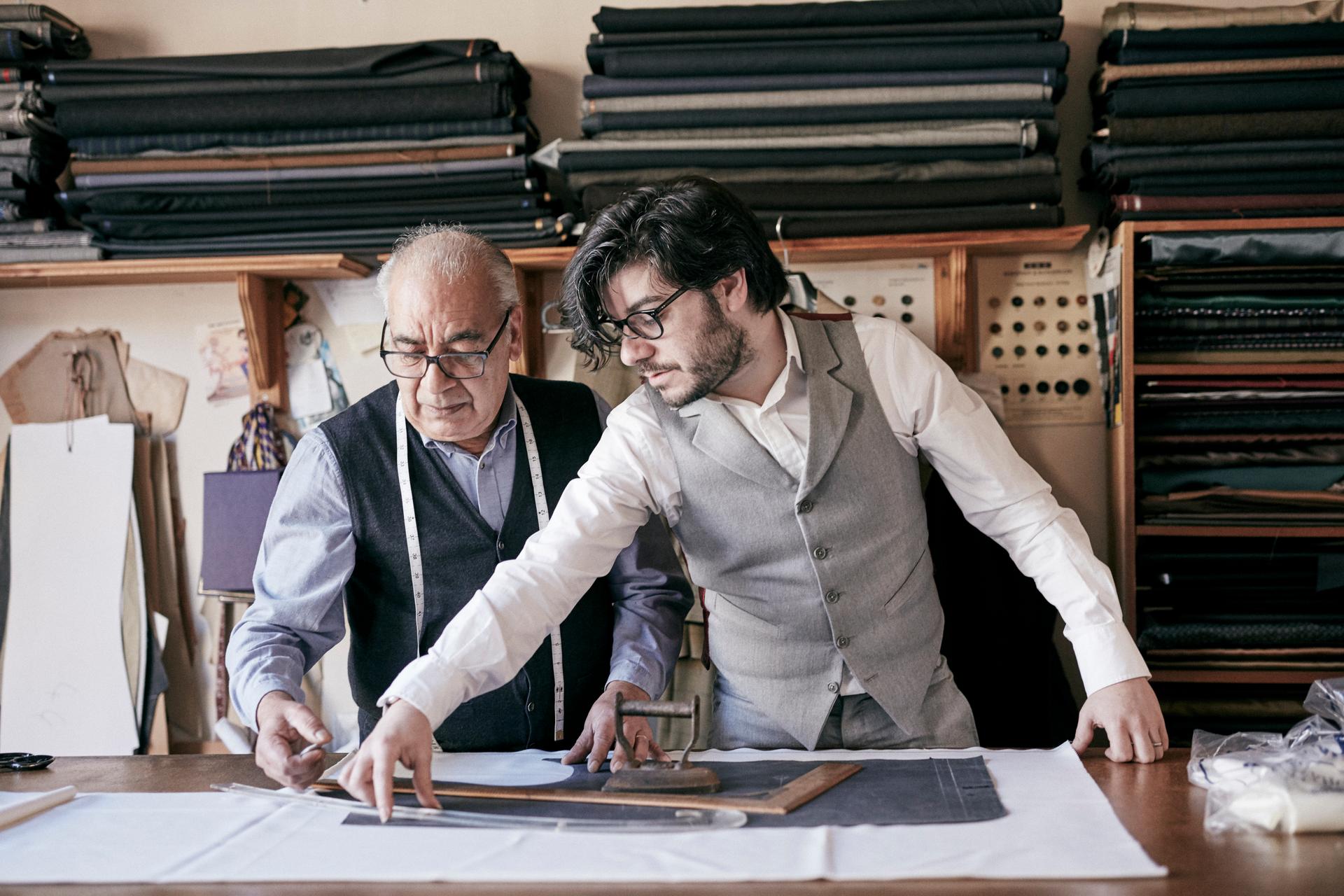 Ein junger Mann arbeitet zusammen mit einem alten Mann in einer Werkstatt mit Stoffen und symbolisiert die Lebensversicherungsdienstleistung von Vontobel.