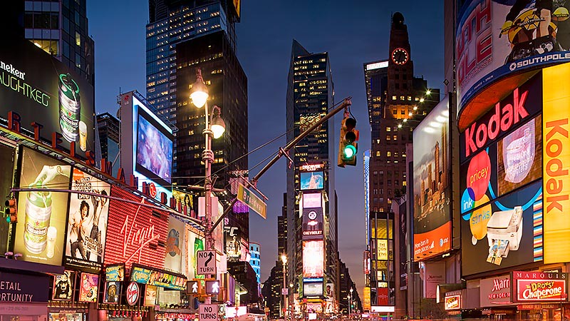 Una grande città di notte con molti cartelloni pubblicitari.