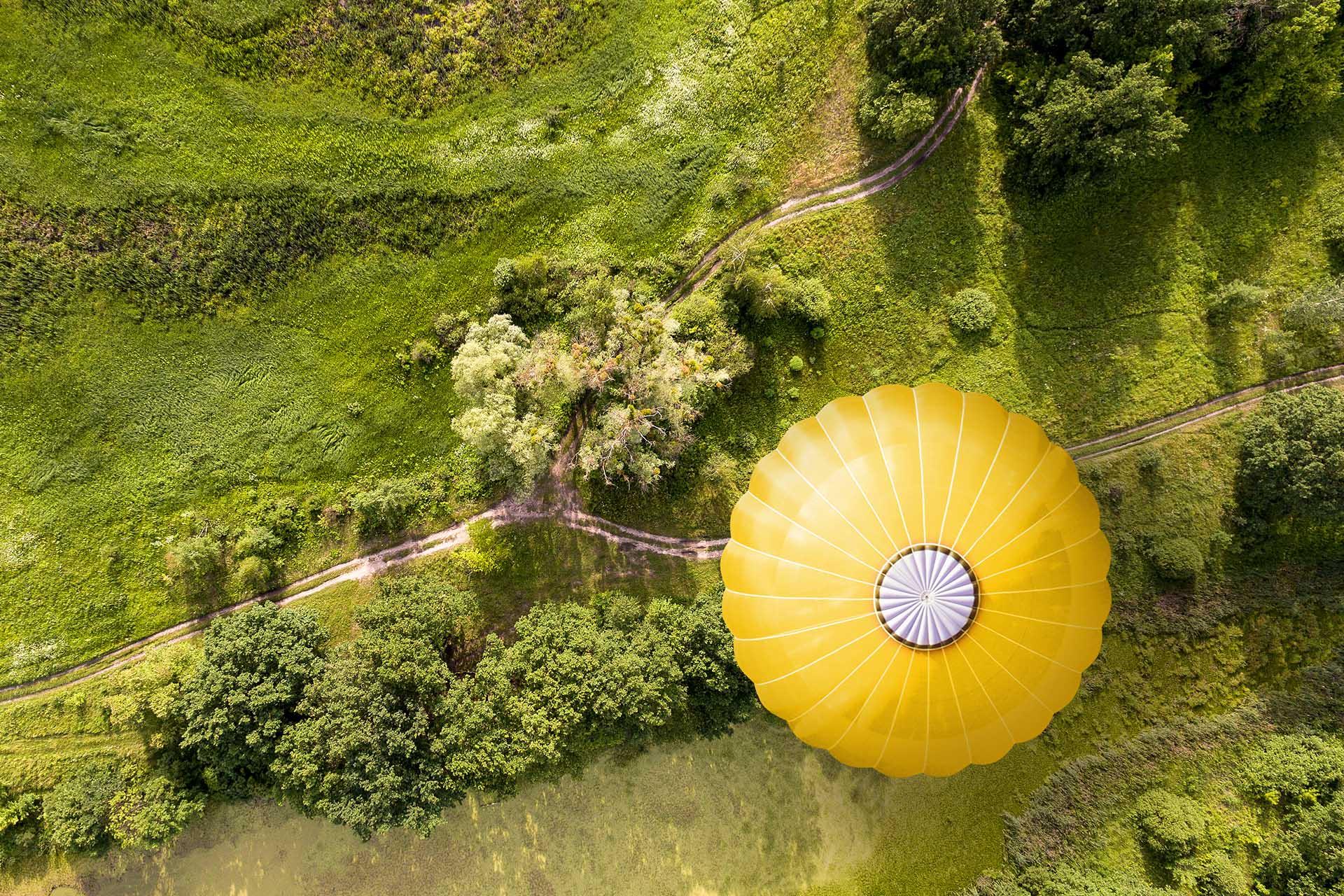 High-yield long-term investment with Vontobel - Bird's-eye view of a yellow hot-air balloon in the countryside
