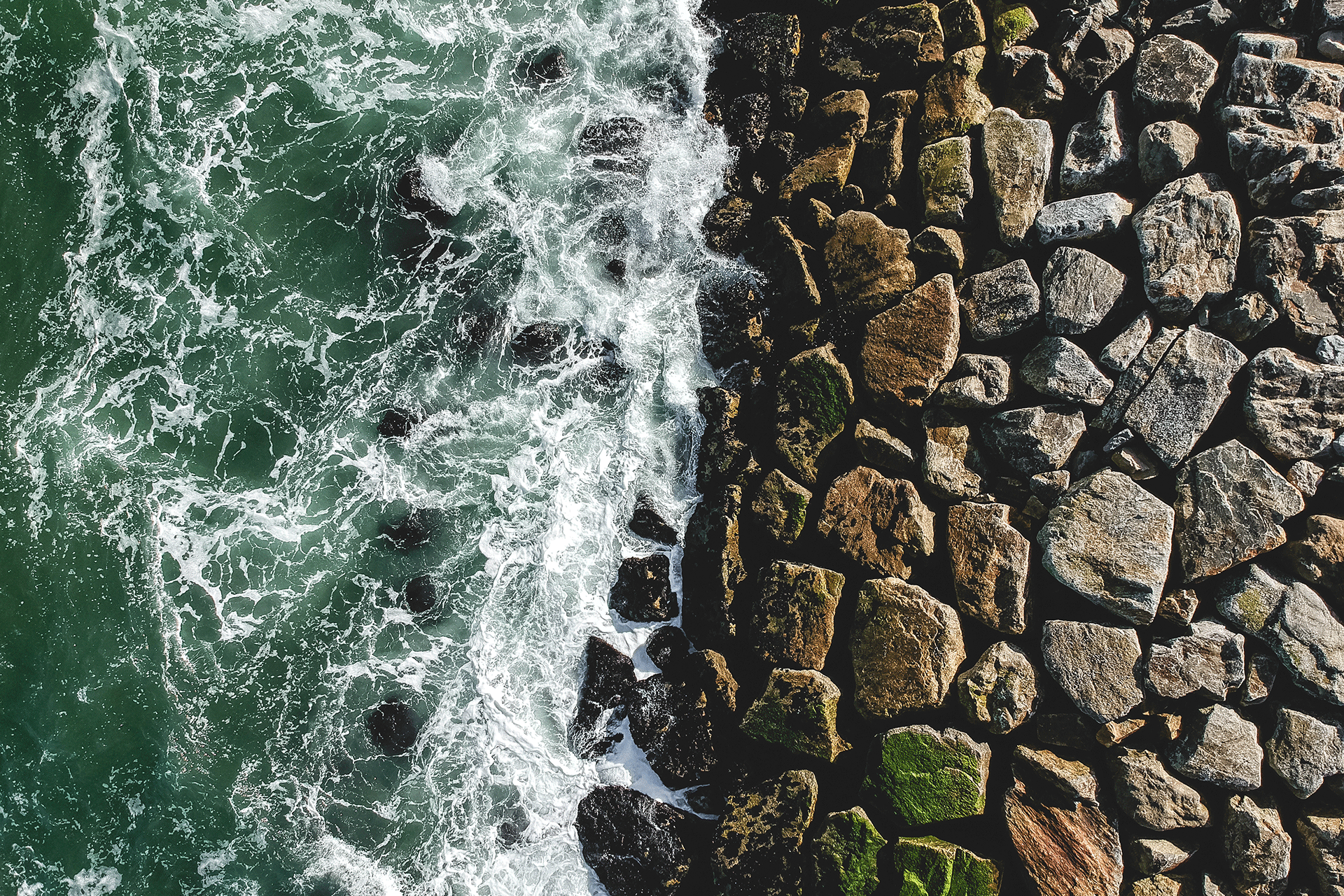 Vue d'en haut des vagues se brisant contre un mur de roche construit - symbolique de l'investissement de qualité.